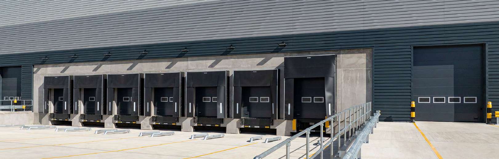 Row of dock level doors with dock levellers and a level access door